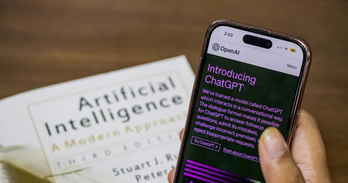 Free Close-up of a smartphone displaying ChatGPT app held over AI textbook.